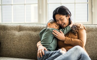 妈妈抱着沙发上的儿子