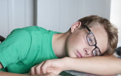 年轻的青少年男孩躺着非常无聊