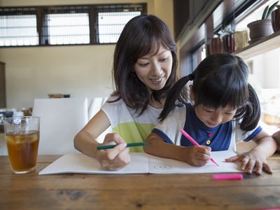 an Asian woman and little girl drawing together