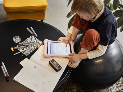 孩子坐在健身球上，在iPad上工作