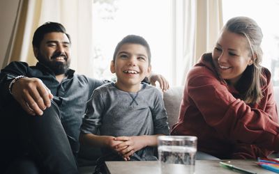 坐在客厅沙发上微笑的父母看着患有自闭症的儿子