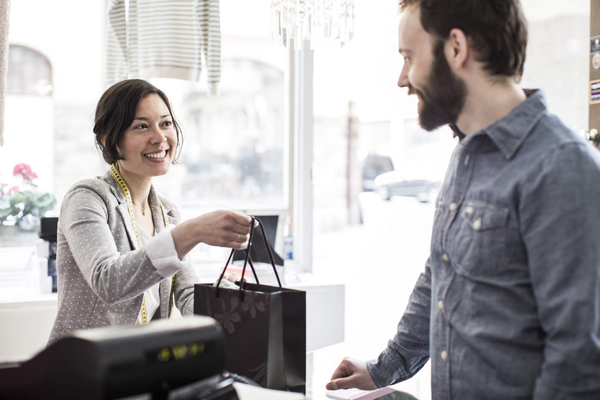 中年女性设计专业给客户购物袋在现金柜台在工作室