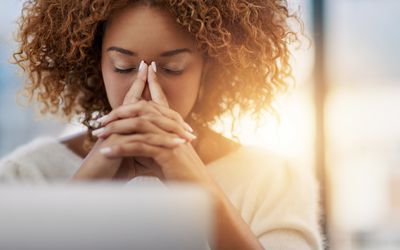 An image of an anxious woman with her hands on her face.