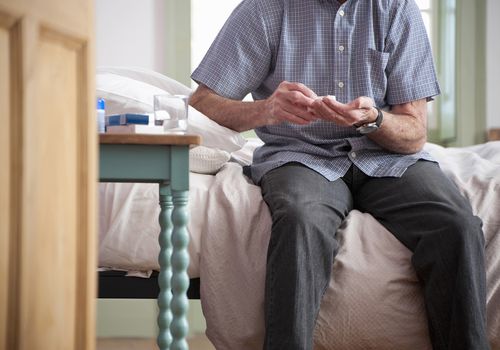 Older man taking pills on bed