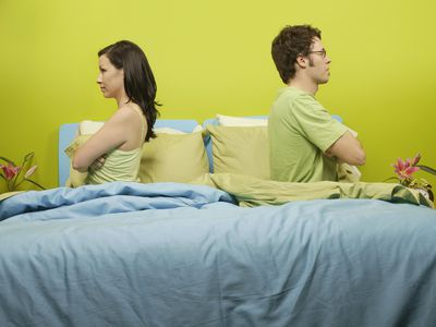 愤怒的夫妇背靠背坐在床上