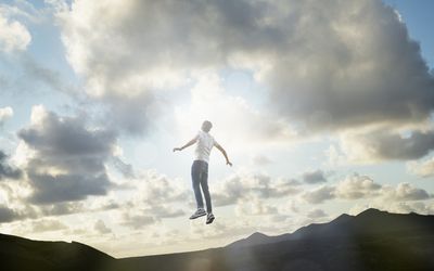 男性在日落的风景中漂浮在云里