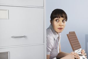 办公室职员躲起来吃一大块巧克力