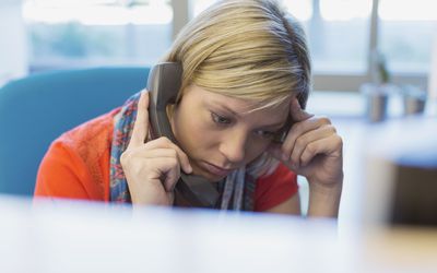 忧心忡忡的女商人在工作中使用电话