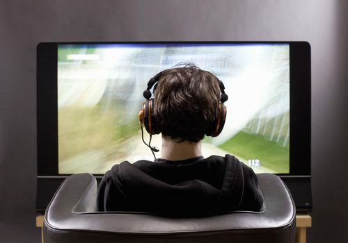 一名年轻男子的头上戴着耳机在电视机前的回