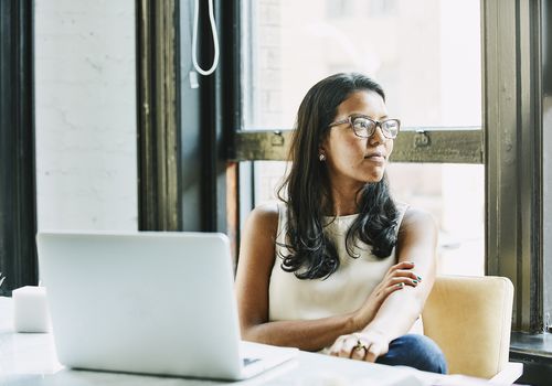 Woman with glasses staring happily out window. Deep in thought.