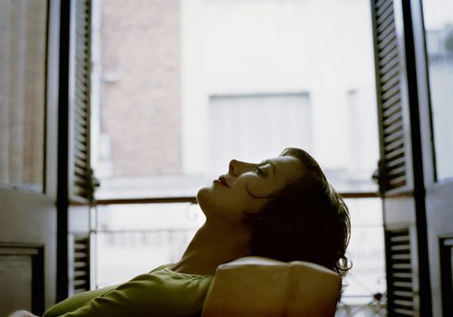 A woman lying back in a chair with her eyes closed.