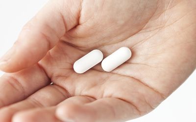 拿着白色药片，手特写镜头的妇女