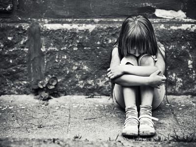 一个吓坏了的孩子在墙边抱着膝盖