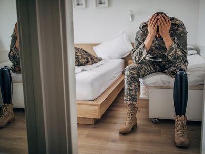 老兵双手抱着头坐在床边