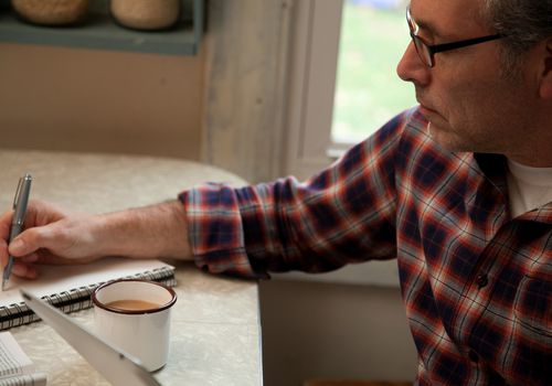 mature man writing at table