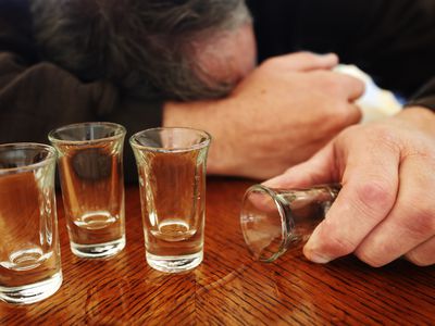 Alcoholism, shot glasses, mature man passed out.