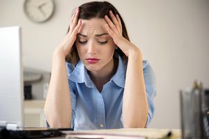 stressed woman with her head in her hands at work desk