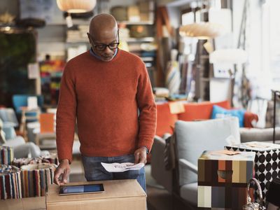 Senior man using digital tablet while reading document at store