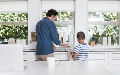 父亲和儿子清洁盘子的背面图在厨房里在家