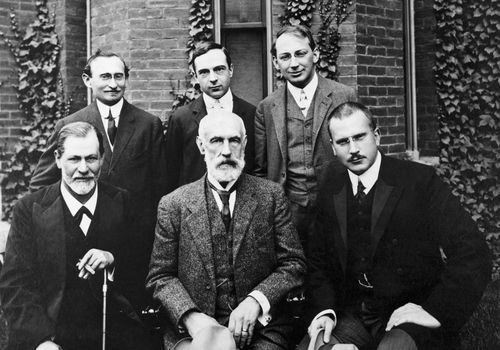 six famous psychologists posing in front of college building