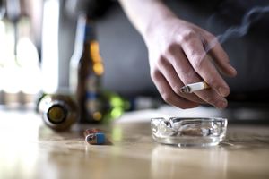 一个人拿着香烟，地上有啤酒瓶