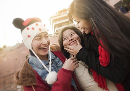 Three female friends laughing and smiling outodoors