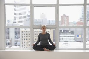一个成熟的女人在一扇以城市为背景的窗户前冥想