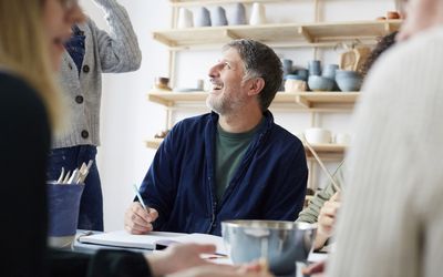 微笑的成熟男学生与女导师在艺术工作室交谈