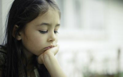 哀伤的孩子看着她的头在她的手上