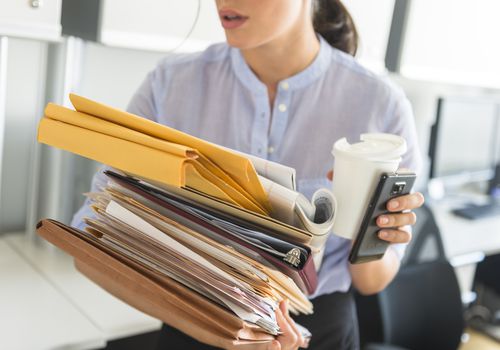 Business woman holding stack of documents in office