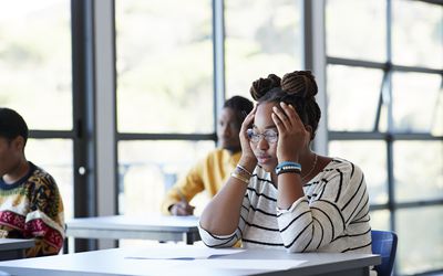 忧心忡忡的学生双手托着头坐在课桌前