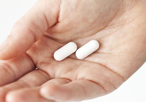 Woman holding white pills, close-up of hand