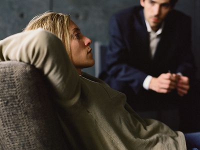 斜倚在长沙发，看她的心理学家的少妇在背景中。