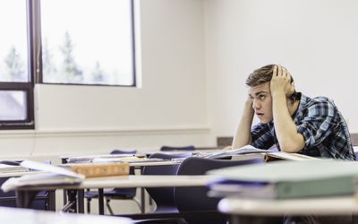 教室里手放在头上的男学生