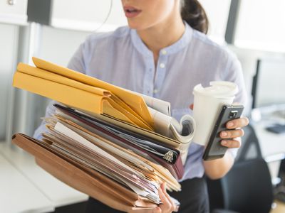 美国，新泽西州，泽西城，一位女商人在办公室里拿着一堆文件