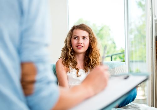 Young girl talking and adult woman's arm with clipboard in the foreground