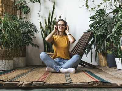 Relaxed young woman sitting on the floor at home listening to music