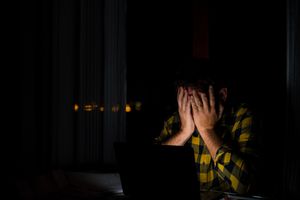 疲惫和沮丧的男人在深夜工作和使用笔记本电脑