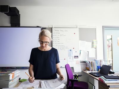 老师在教室里对着白板批改试卷