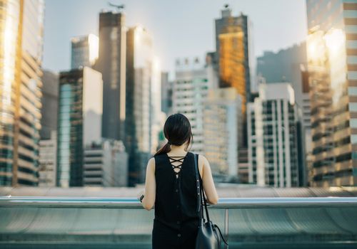 女人的后视图在城市城市景观的天空