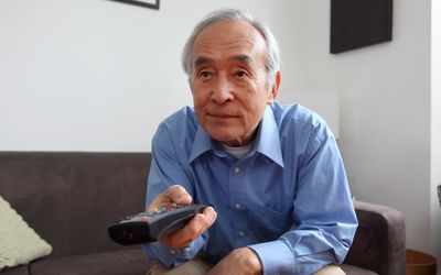 中年男子坐在沙发上翻看电视频道