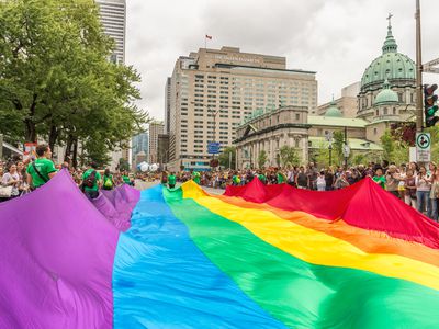 人们在街道上拿着一个巨型同性恋彩虹旗子在同性恋骄傲游行。