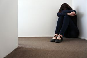 哭泣在地板上的妇女“class=