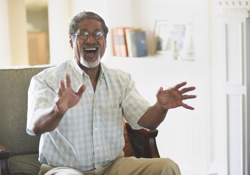 older man smiling and using his hands while telling a story