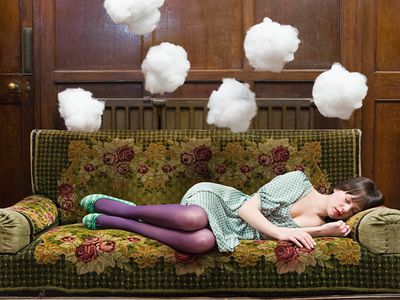 躺在沙发上打盹的女人，头上飘着云