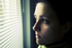 Woman with tear in her eye staring out a window