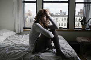 Woman sitting on her bed looking depressed