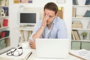 用笔记本电脑工作的男人，擦额头